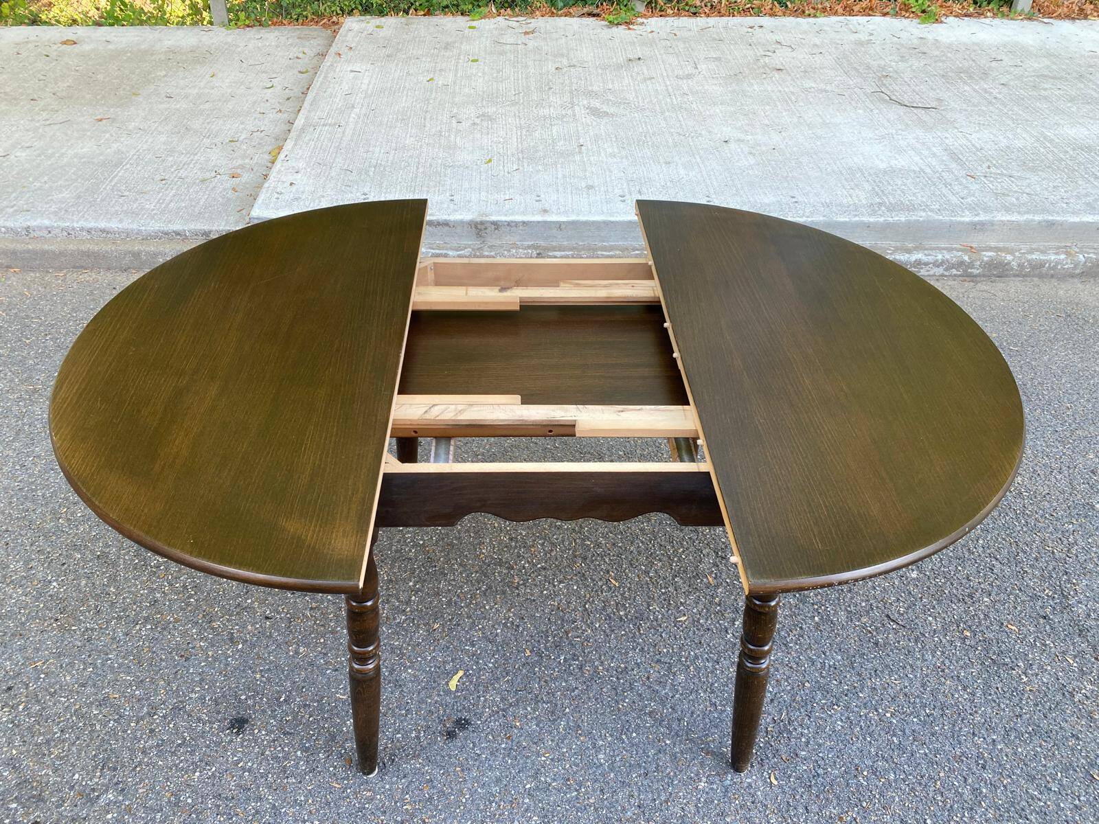 Extendable round table in solid wood with a dark oak satin finish.