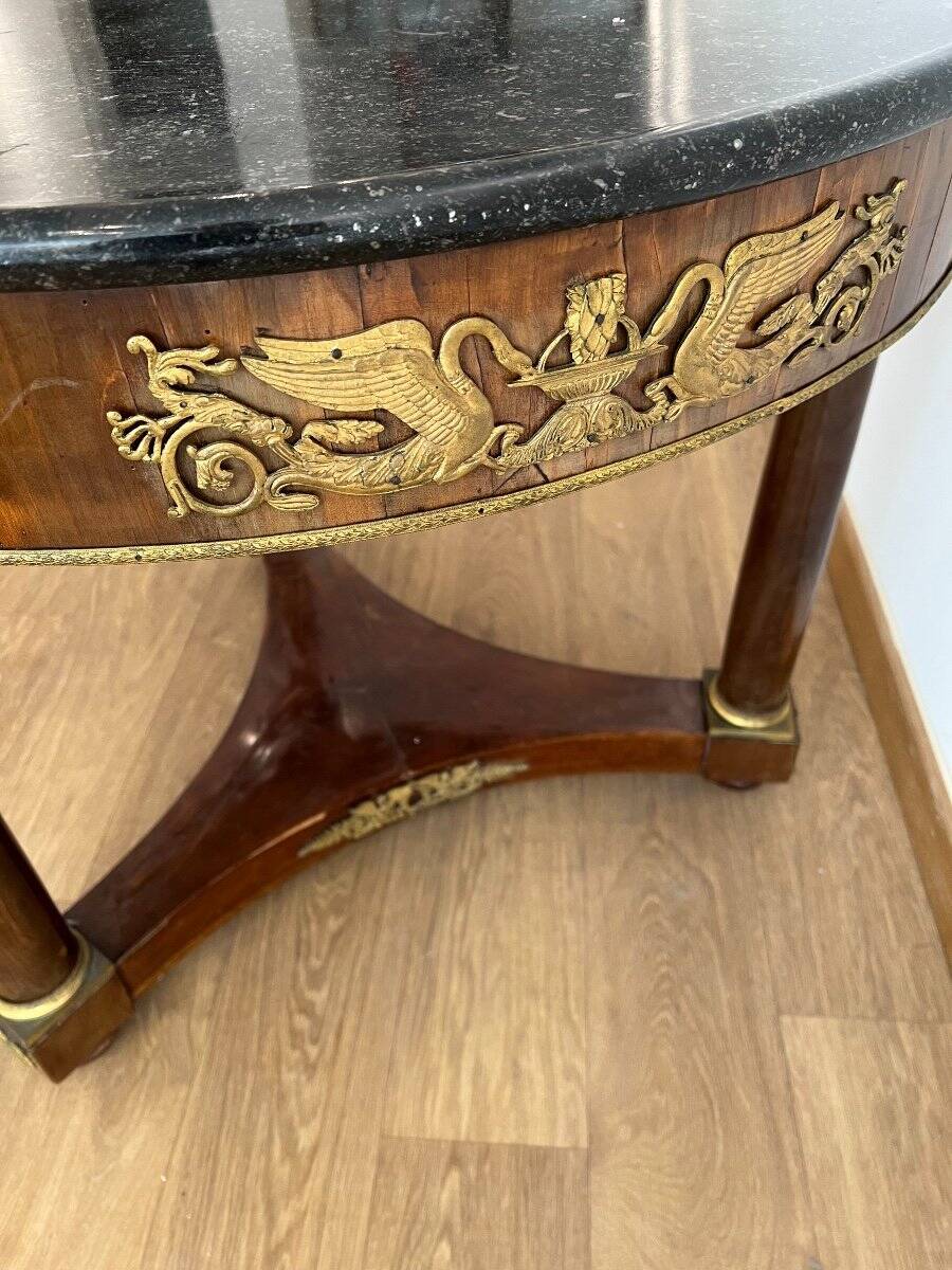 Empire gueridon in mahogany veneer adorned with chiselled and gilded bronze, topped with black marble with a groove.