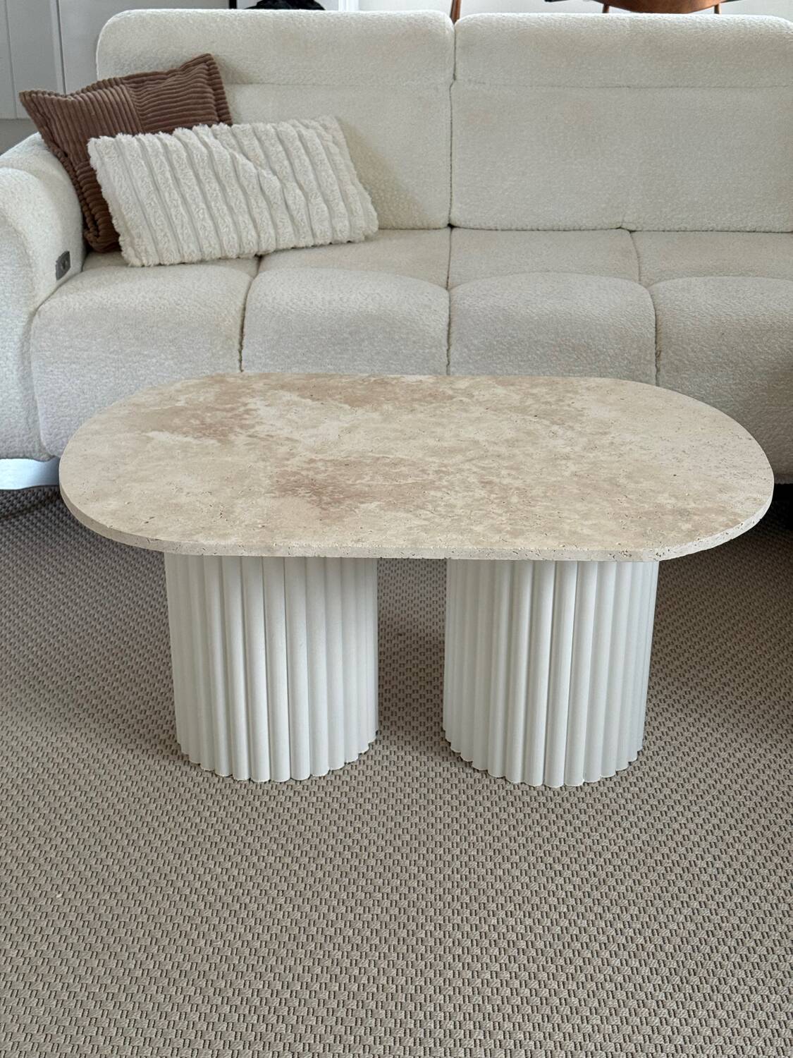 Oval coffee table in travertine and white fluted wood.