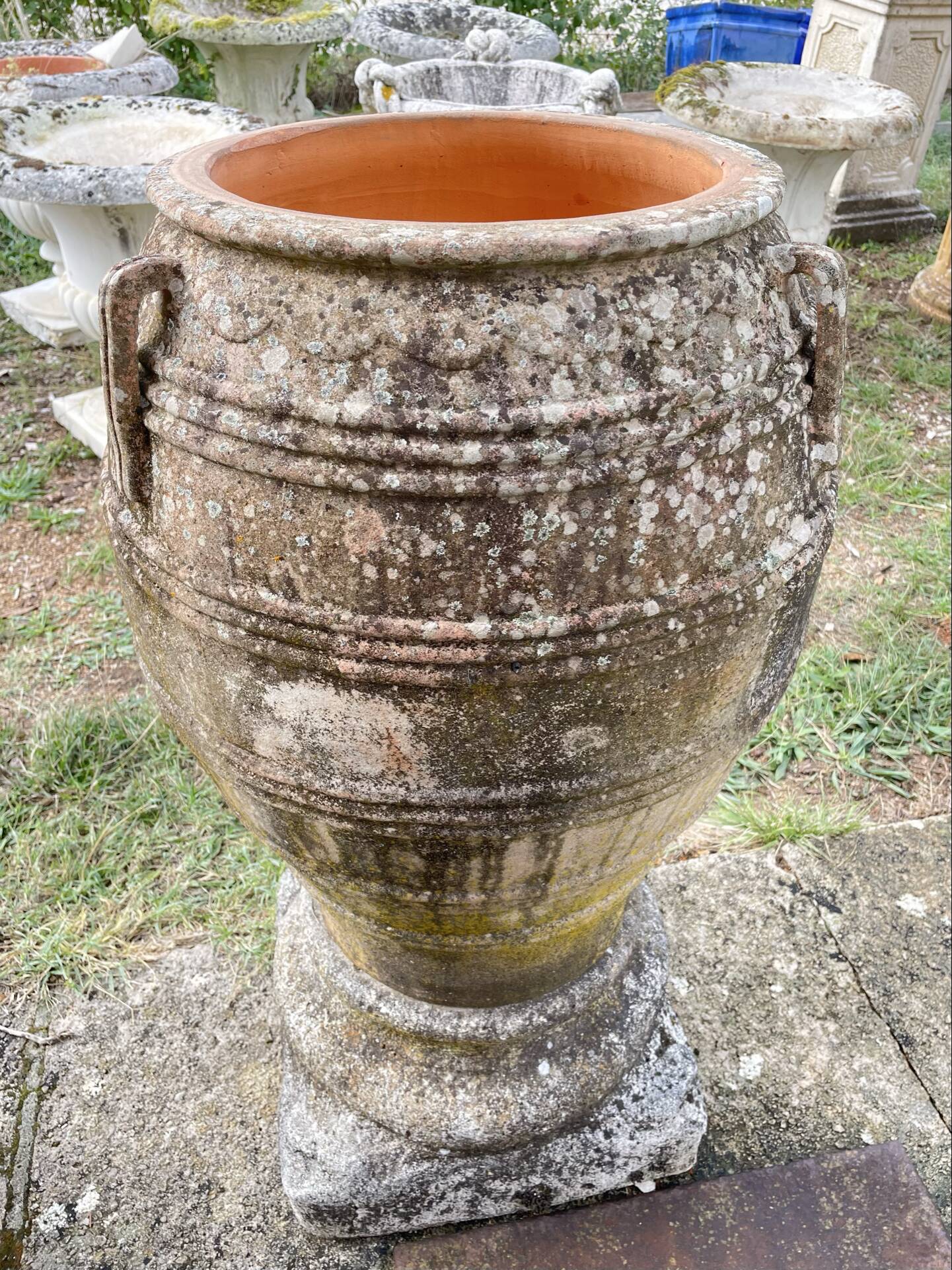 Large Cretan jar in terracotta with three handles on a stone base.
