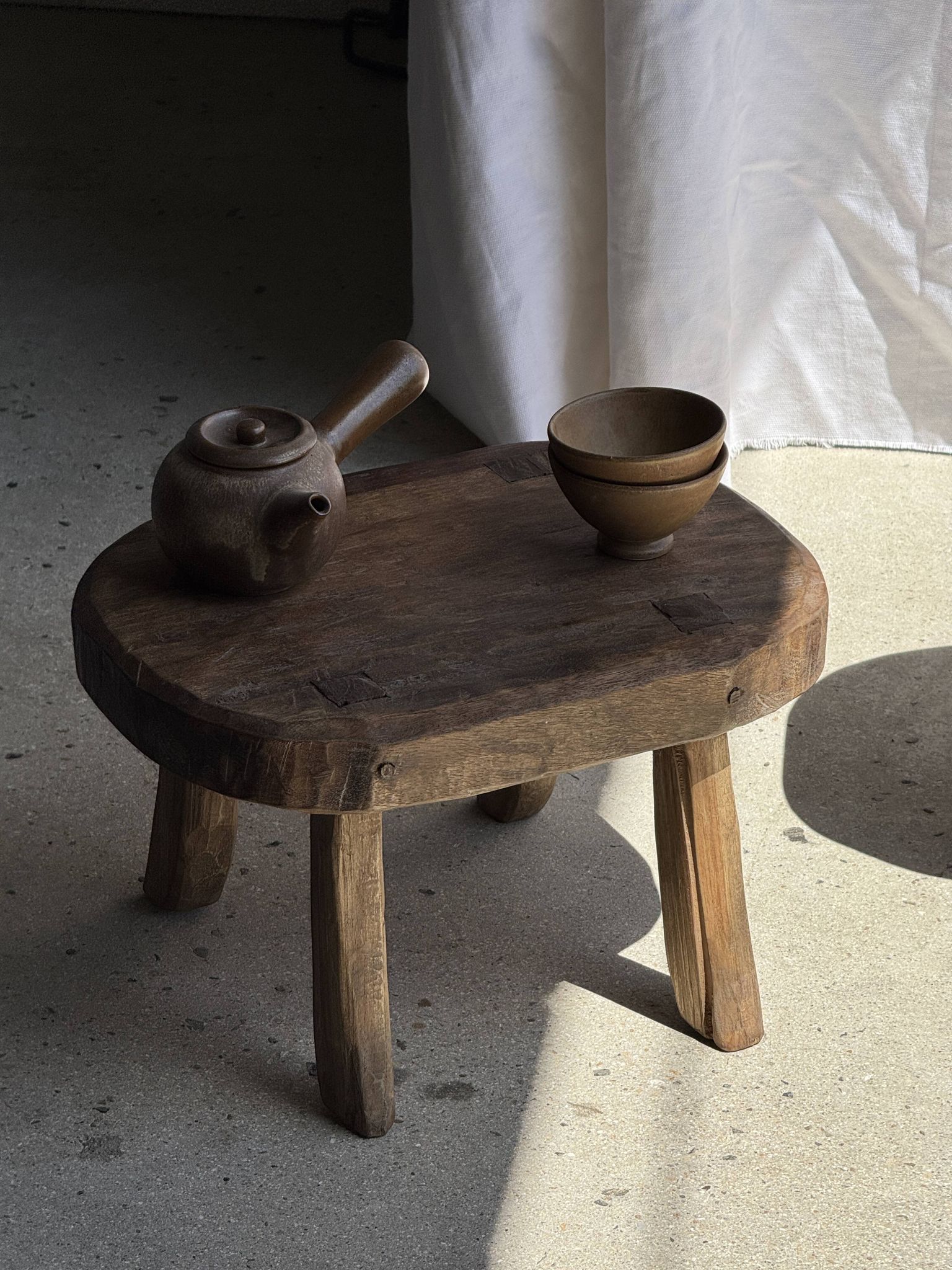 Small stool, oval solid teak side table with curved legs in wabi-sabi style.