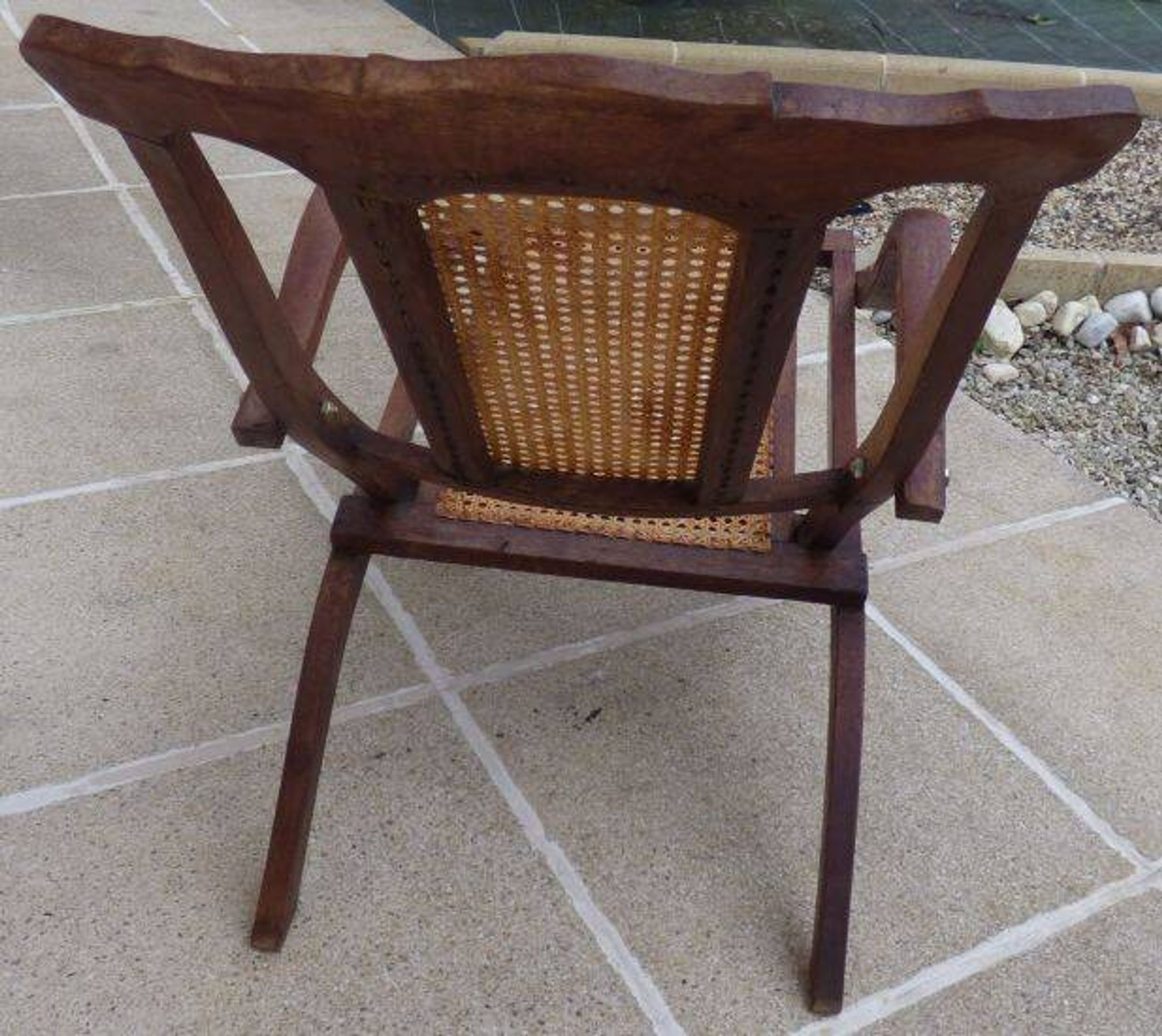 Antique folding chair with caned seat and backrest made of wood.