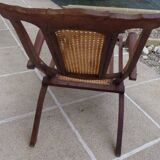 Antique folding chair with caned seat and backrest made of wood.
