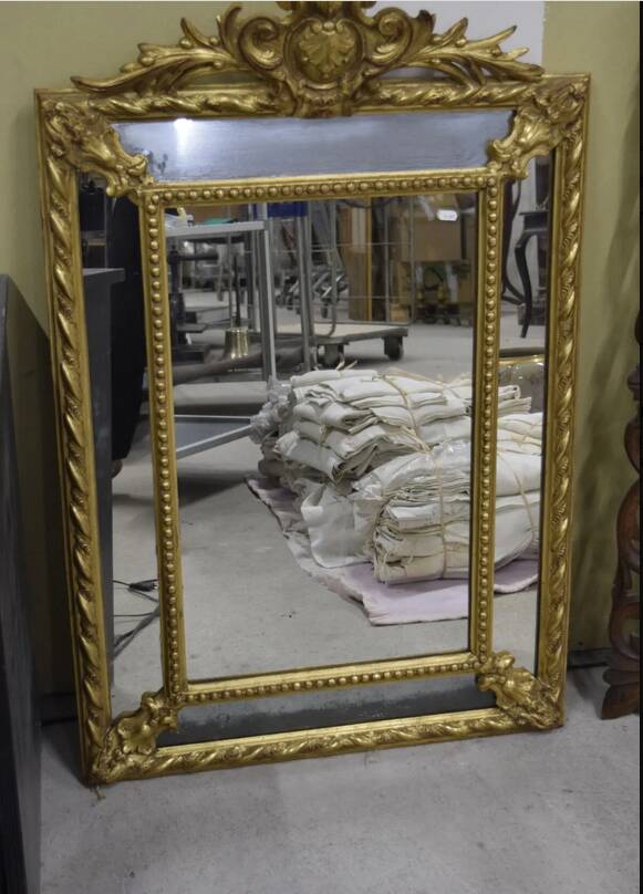 Rectangular glass with a golden frame and a pediment adorned with laurel branches.