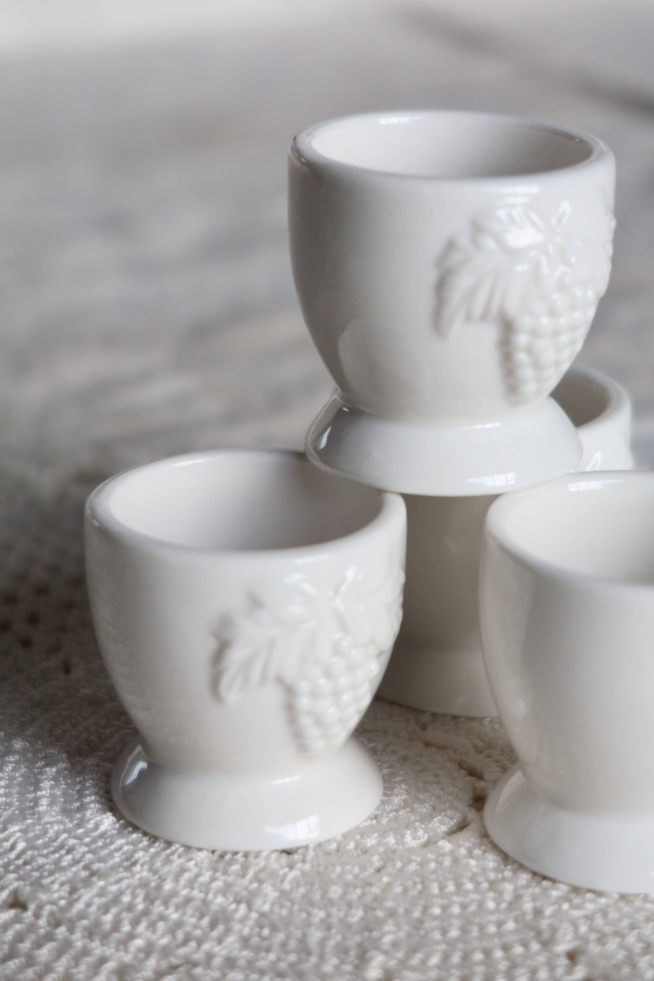 Vintage white porcelain egg cups with fruit motif.