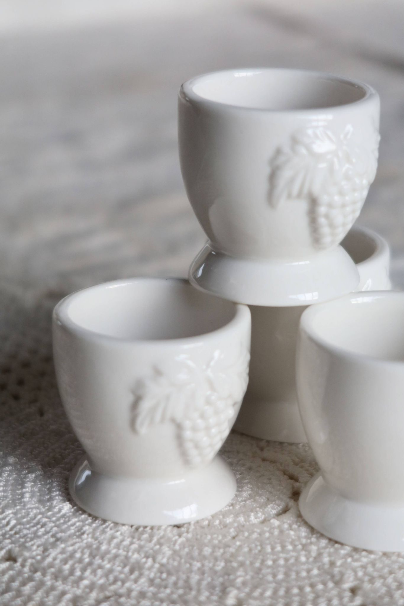 Vintage white porcelain egg cups with fruit motif.