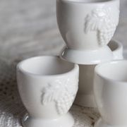 Vintage white porcelain egg cups with fruit motif.