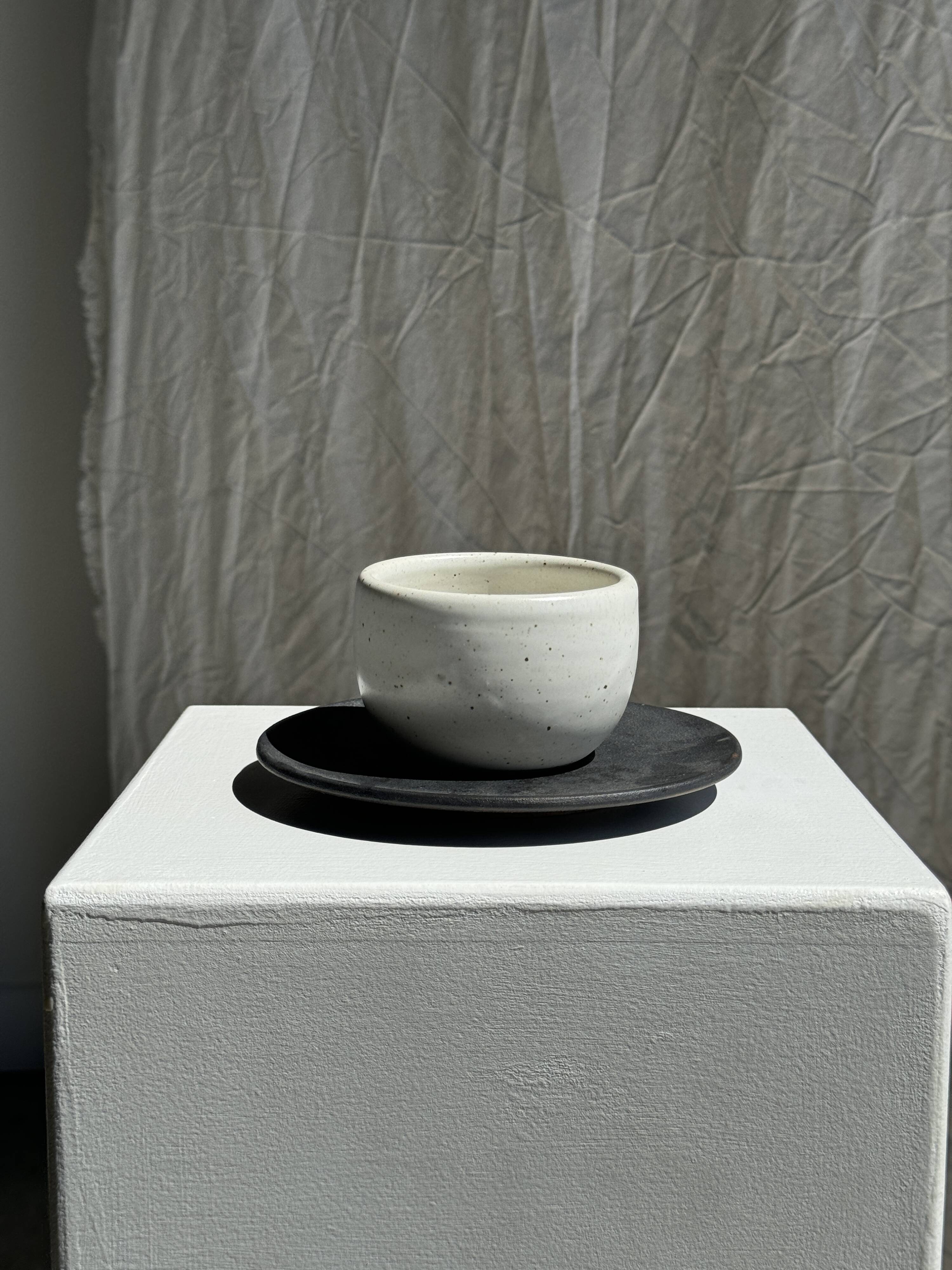 White Indonesian ceramic cup and gray saucer