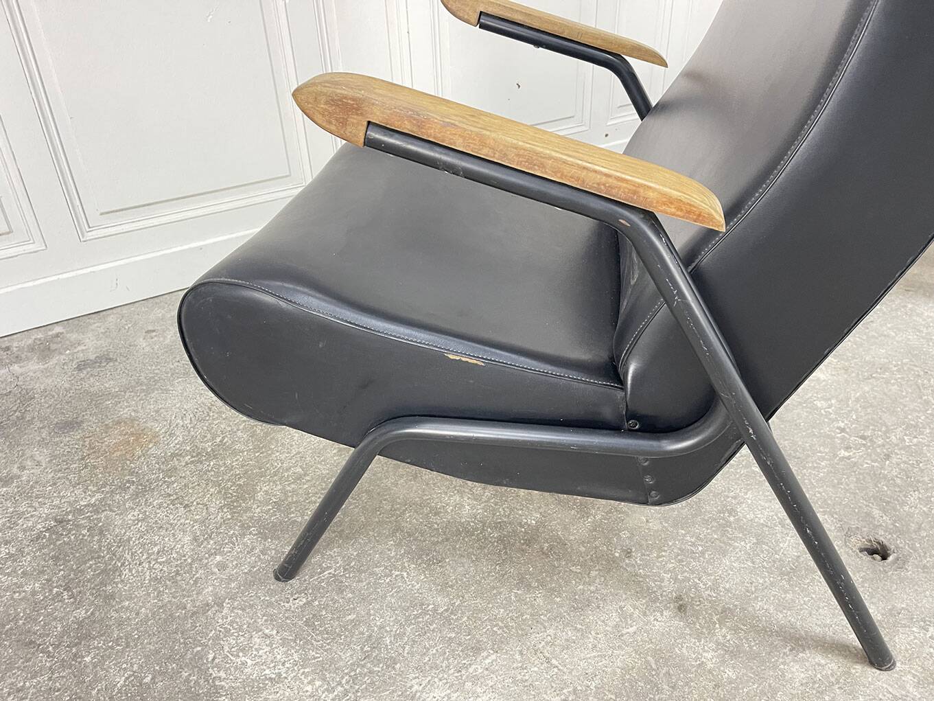 A pair of vintage armchairs in black faux leather.