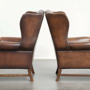 Ensemble de 2 fauteuils à oreilles en cuir de vache de style anglais.