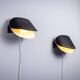 Matte black wall lamps with perforated shades and brass details