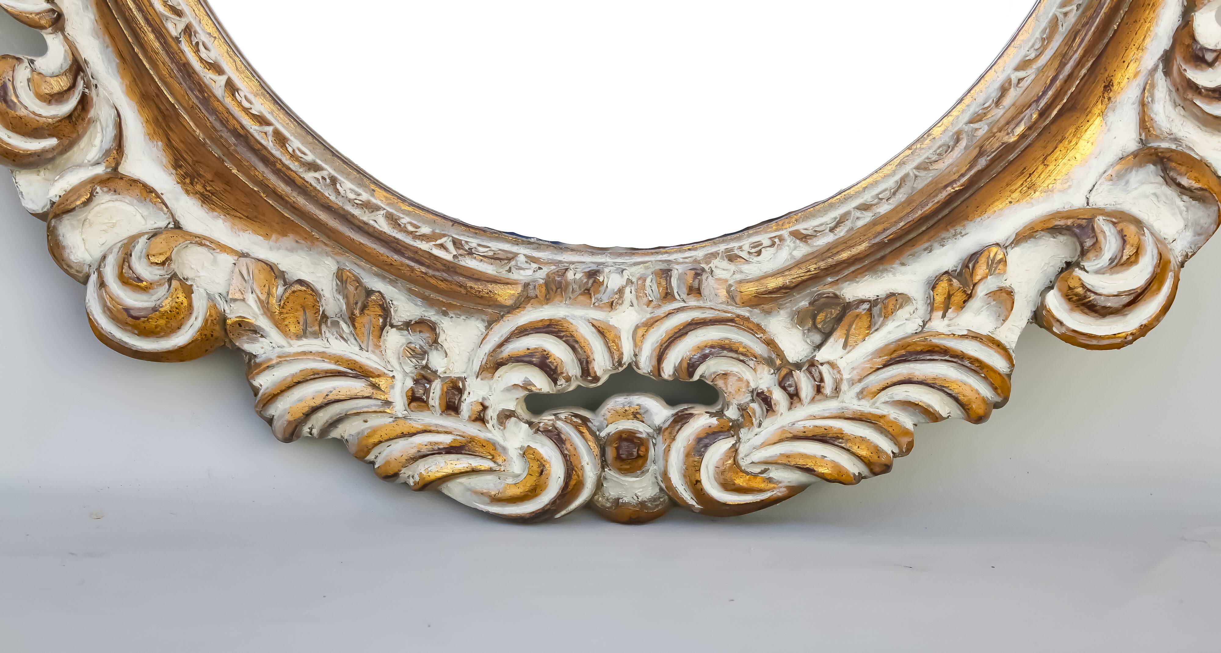 Distressed and carved golden oval mirror in wood.