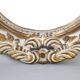 Distressed and carved golden oval mirror in wood.
