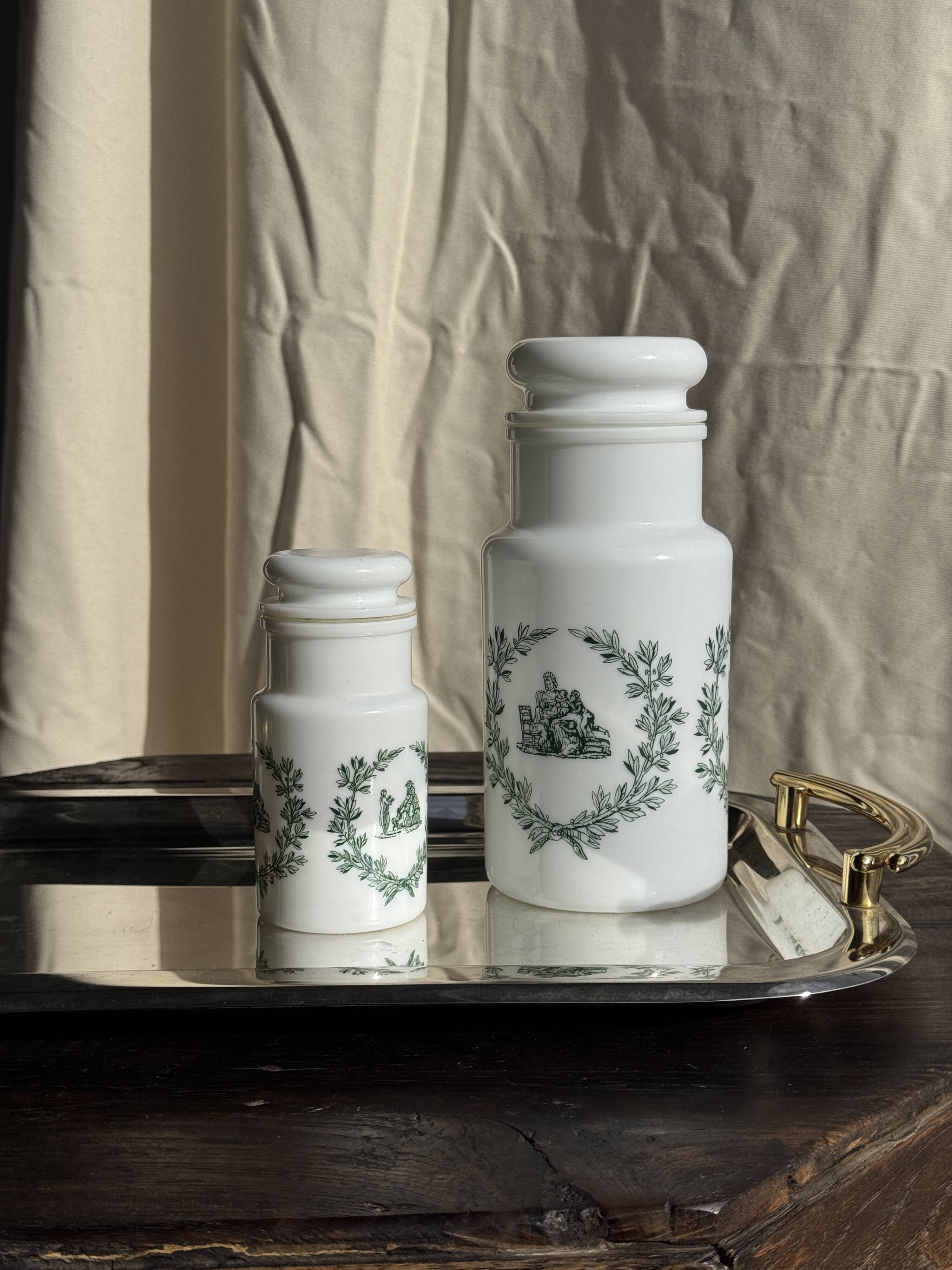A pair of white glass bottles with Italian green patterns.