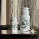 A pair of white glass bottles with Italian green patterns.