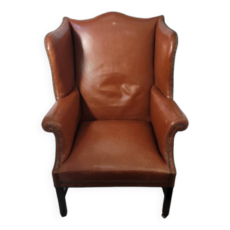 fauteuil à oreilles anglais, tapissé de cuir cognac lisse avec des clous et des pieds en bois