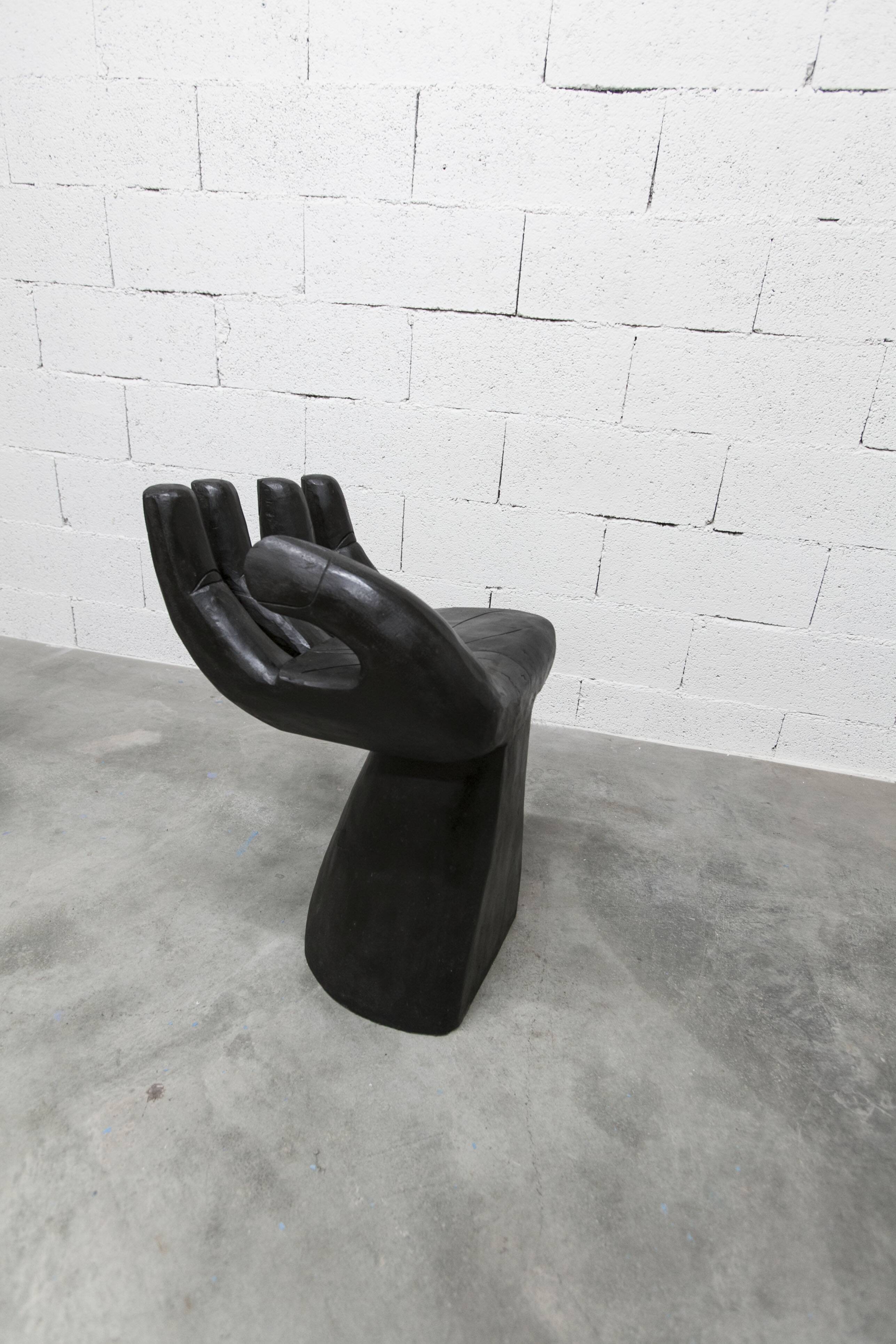 Black armchair chair in carved wood in the shape of a hand