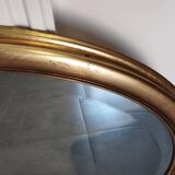 Large and elegant oval gilded mirror with its beveled glass