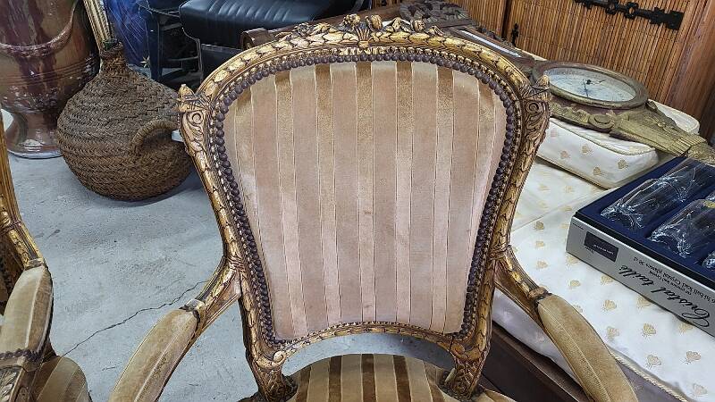 A pair of gilded wooden armchairs in the Louis XVI style.