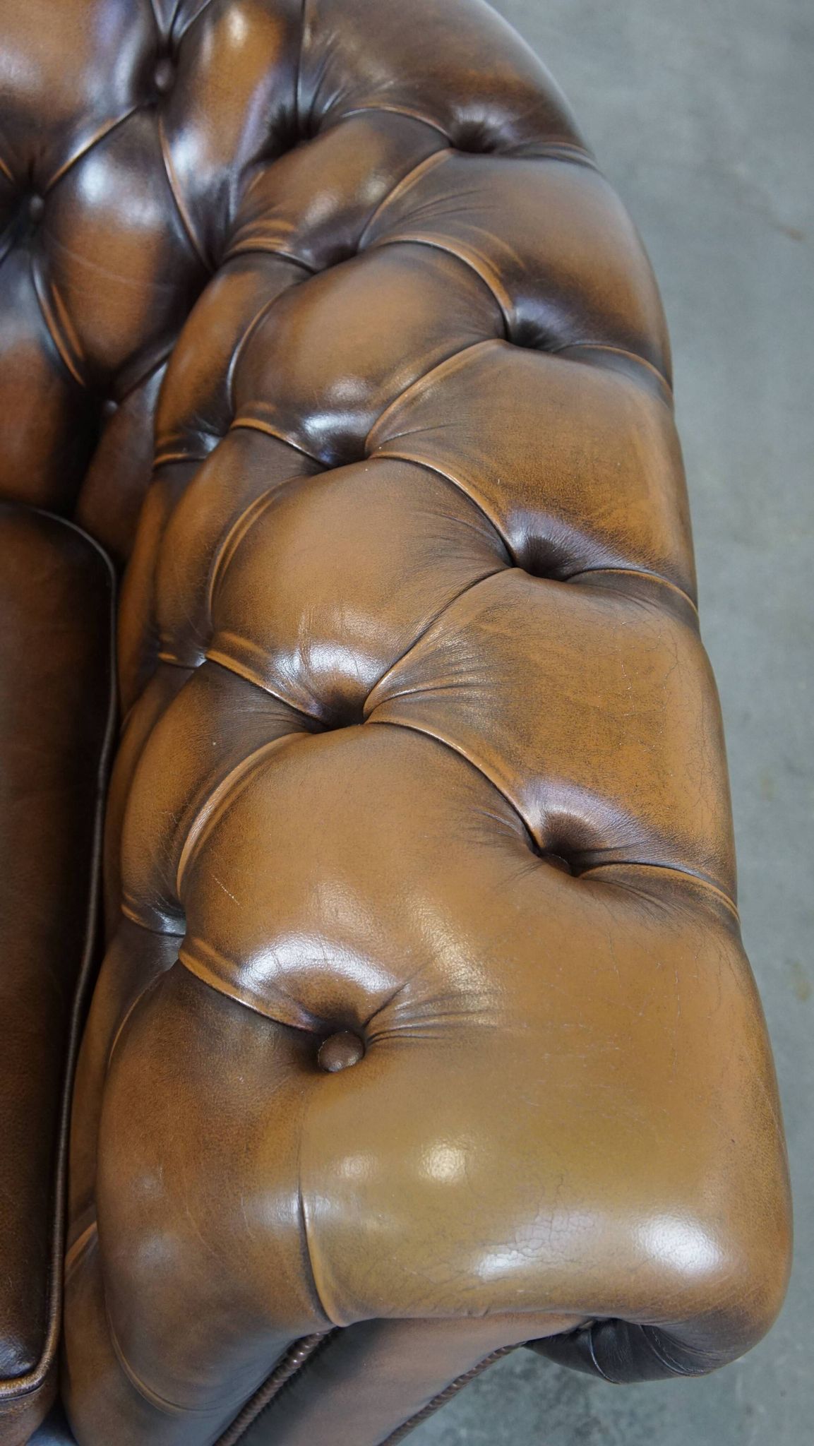 A well-maintained cowhide leather English Chesterfield armchair