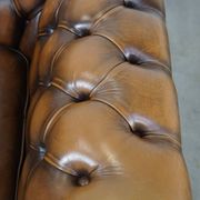 A well-maintained cowhide leather English Chesterfield armchair