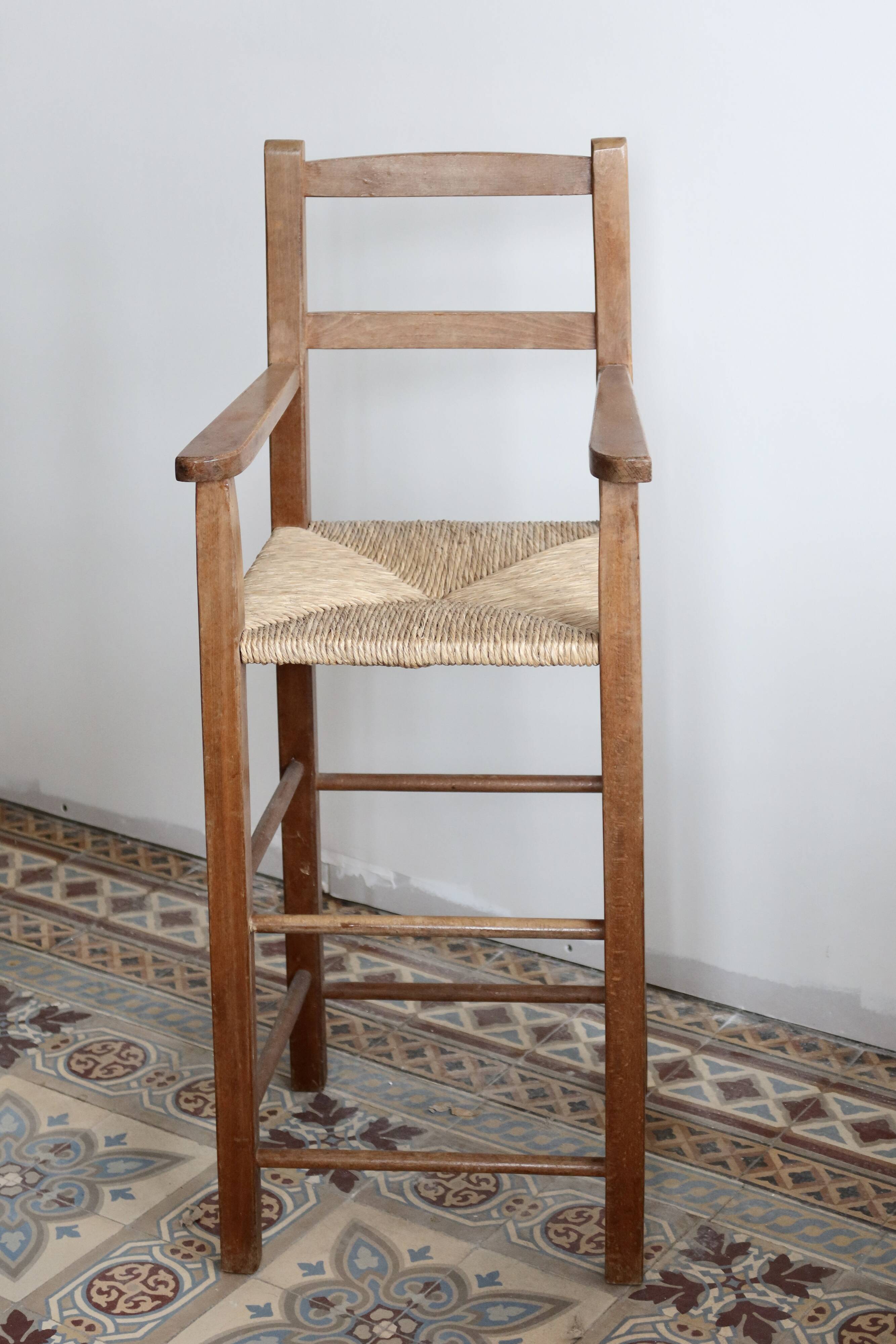 Vintage wooden high chair for children with a straw seat.