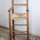 Vintage wooden high chair for children with a straw seat.