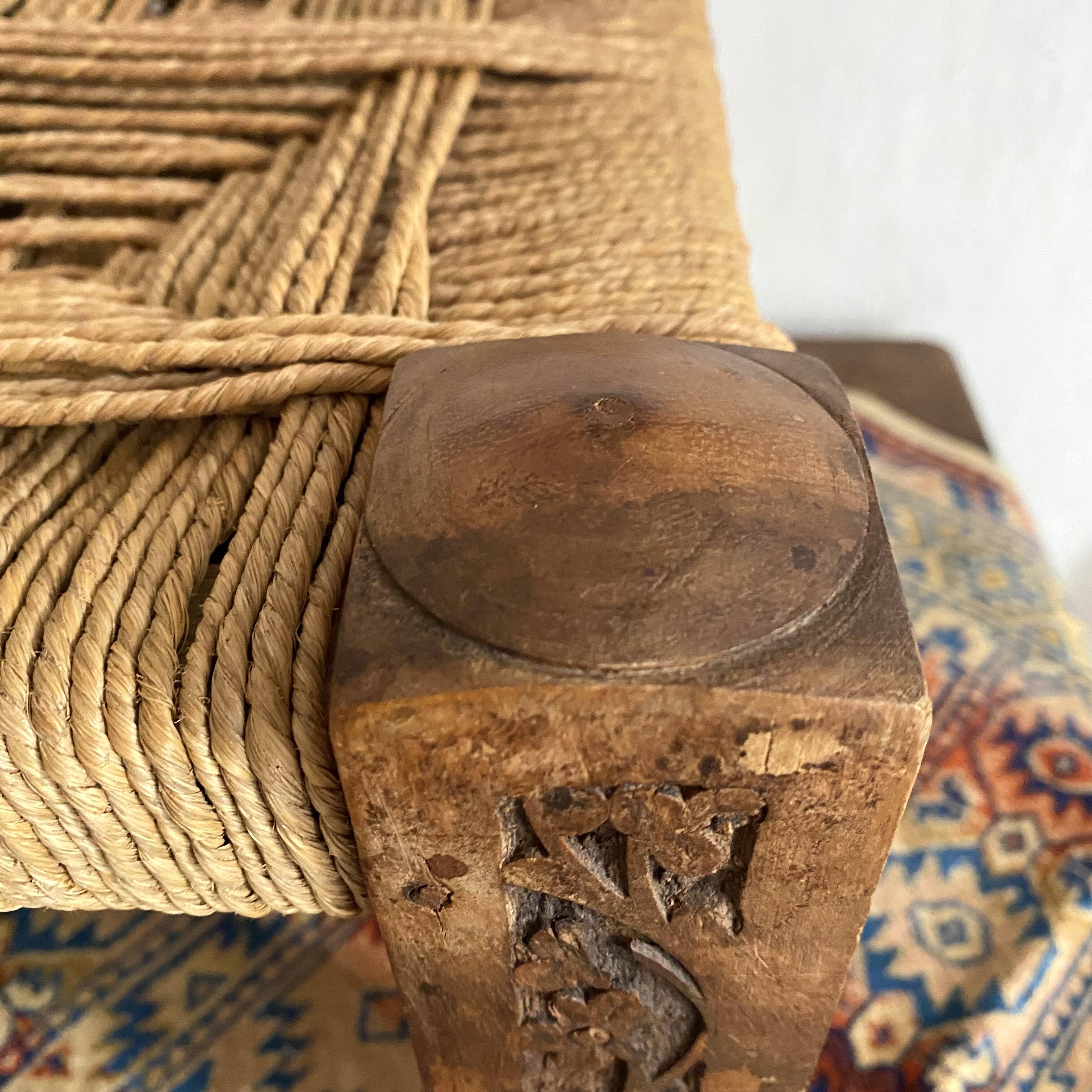 Low stool with carved wood and braided cord.