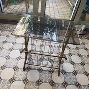 Vintage style side table with magazine holder, gold metal and glass top.