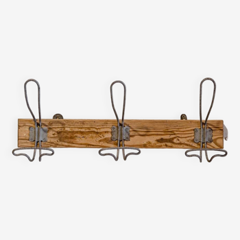 Workshop coat rack -> composed of three vintage steel hooks -> on raw wooden support. I