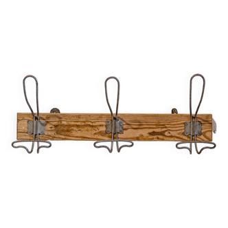 Workshop coat rack -> composed of three vintage steel hooks -> on raw wooden support. I