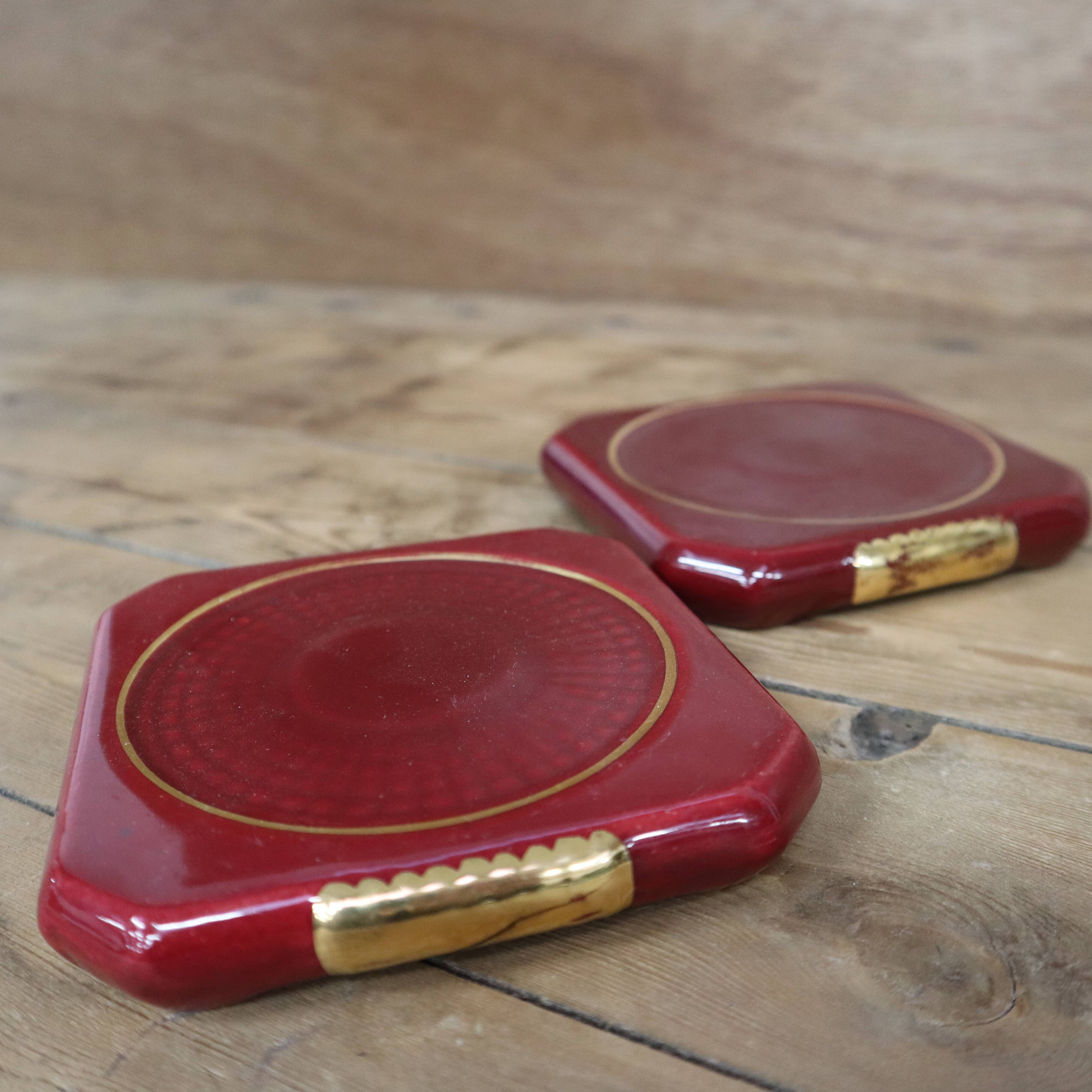 Pair of burgundy ceramic coasters or bottles with gold trim