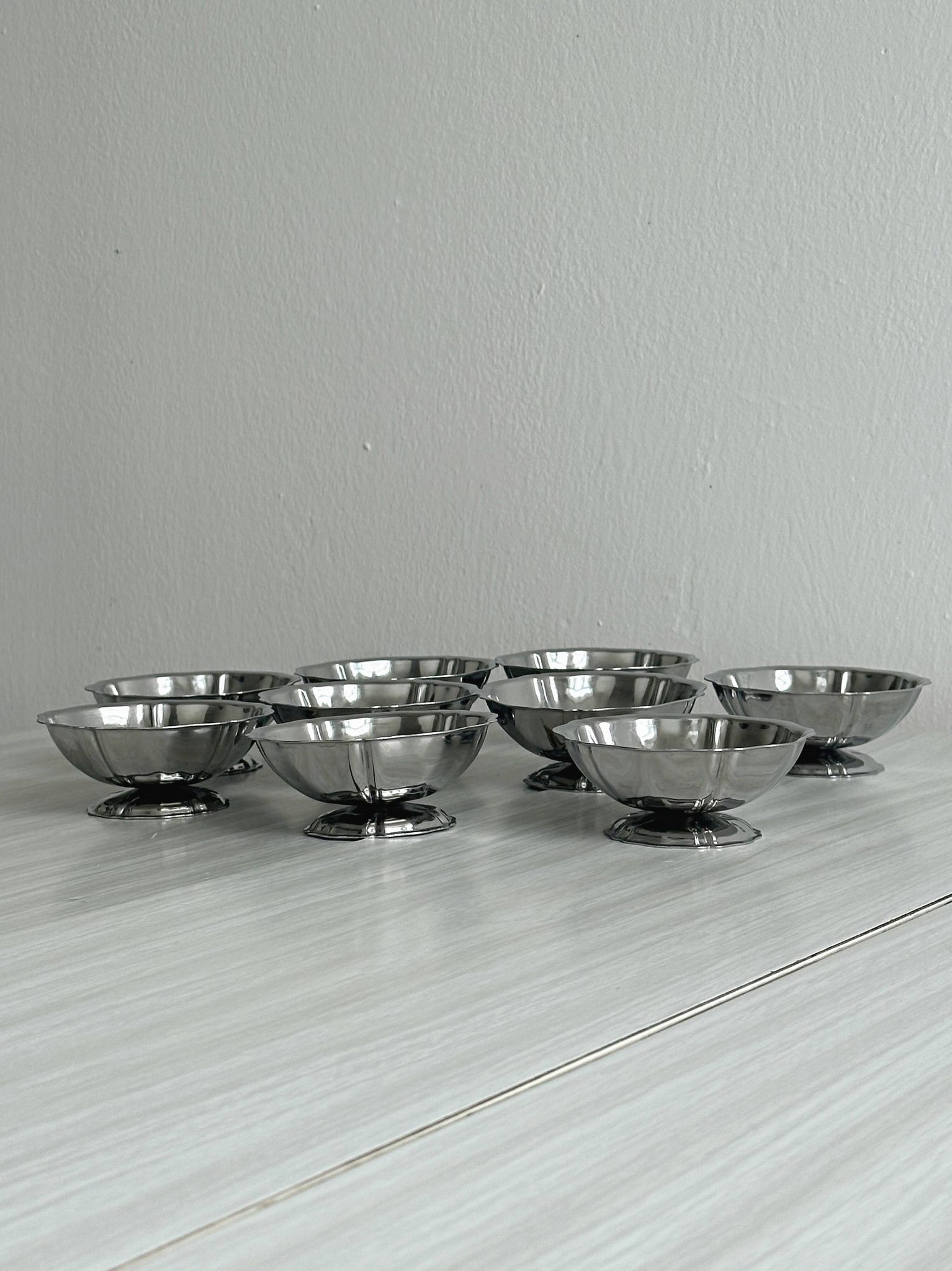 Set of 9 low bowls in shiny stainless steel.