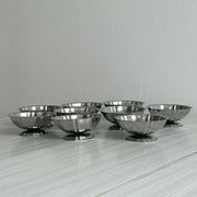 Set of 9 low bowls in shiny stainless steel.