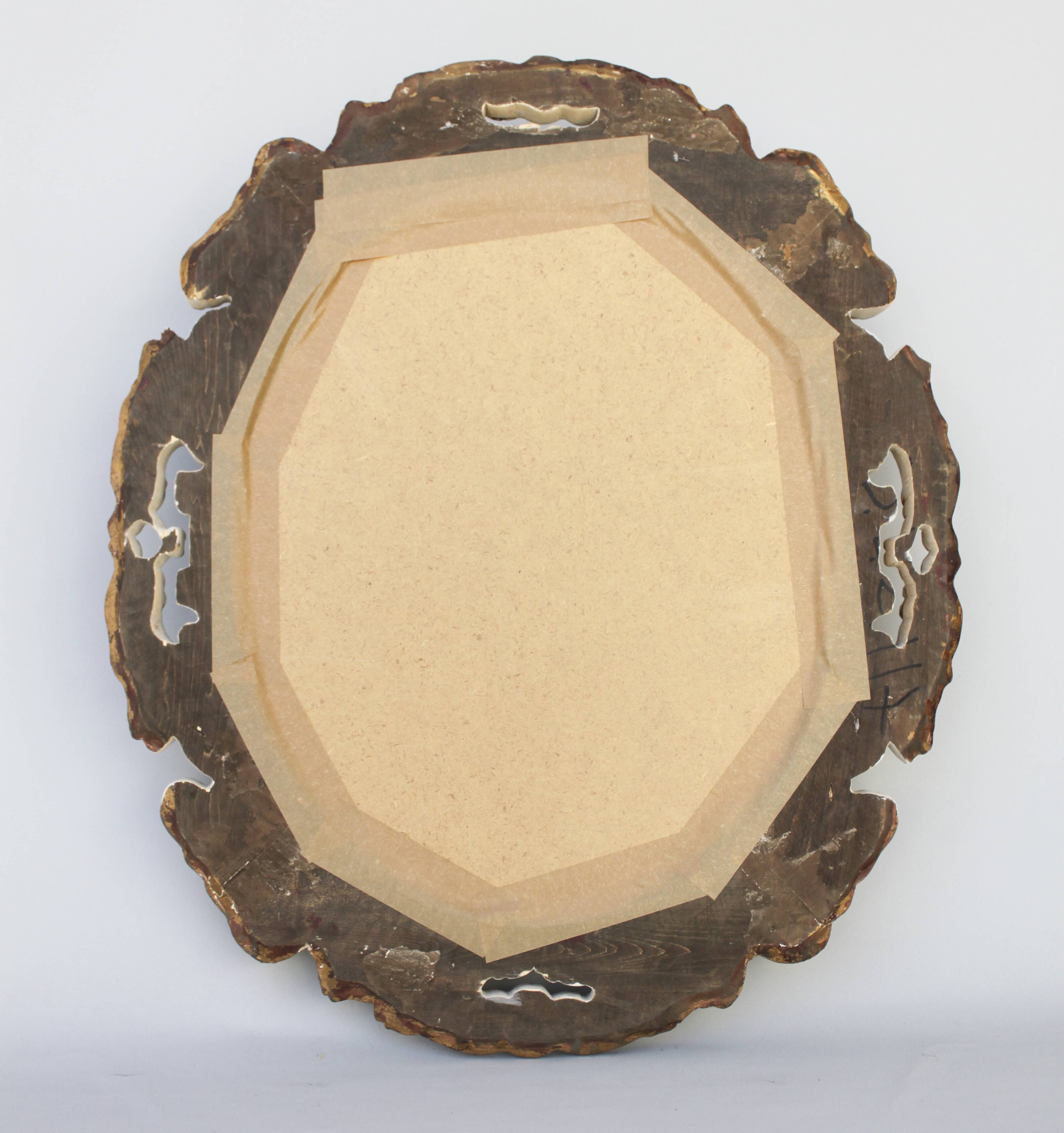 Distressed and carved golden oval mirror in wood.