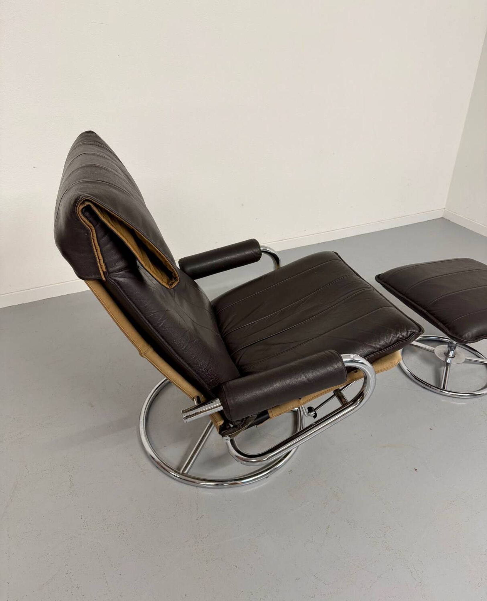 Vintage leather reclining armchair and its 1970s designer ottoman.