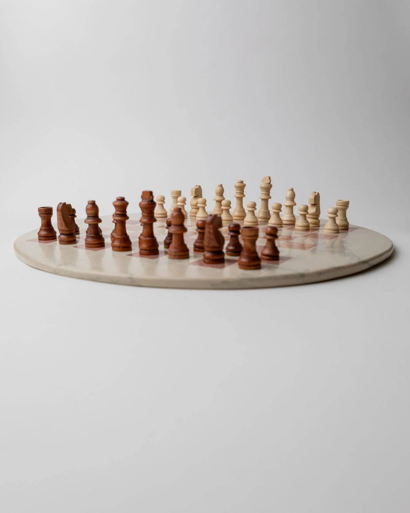 Vintage 1980s round chess set in marble, with a beige and pink marble board and wooden pieces.