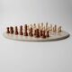 Vintage 1980s round chess set in marble, with a beige and pink marble board and wooden pieces.