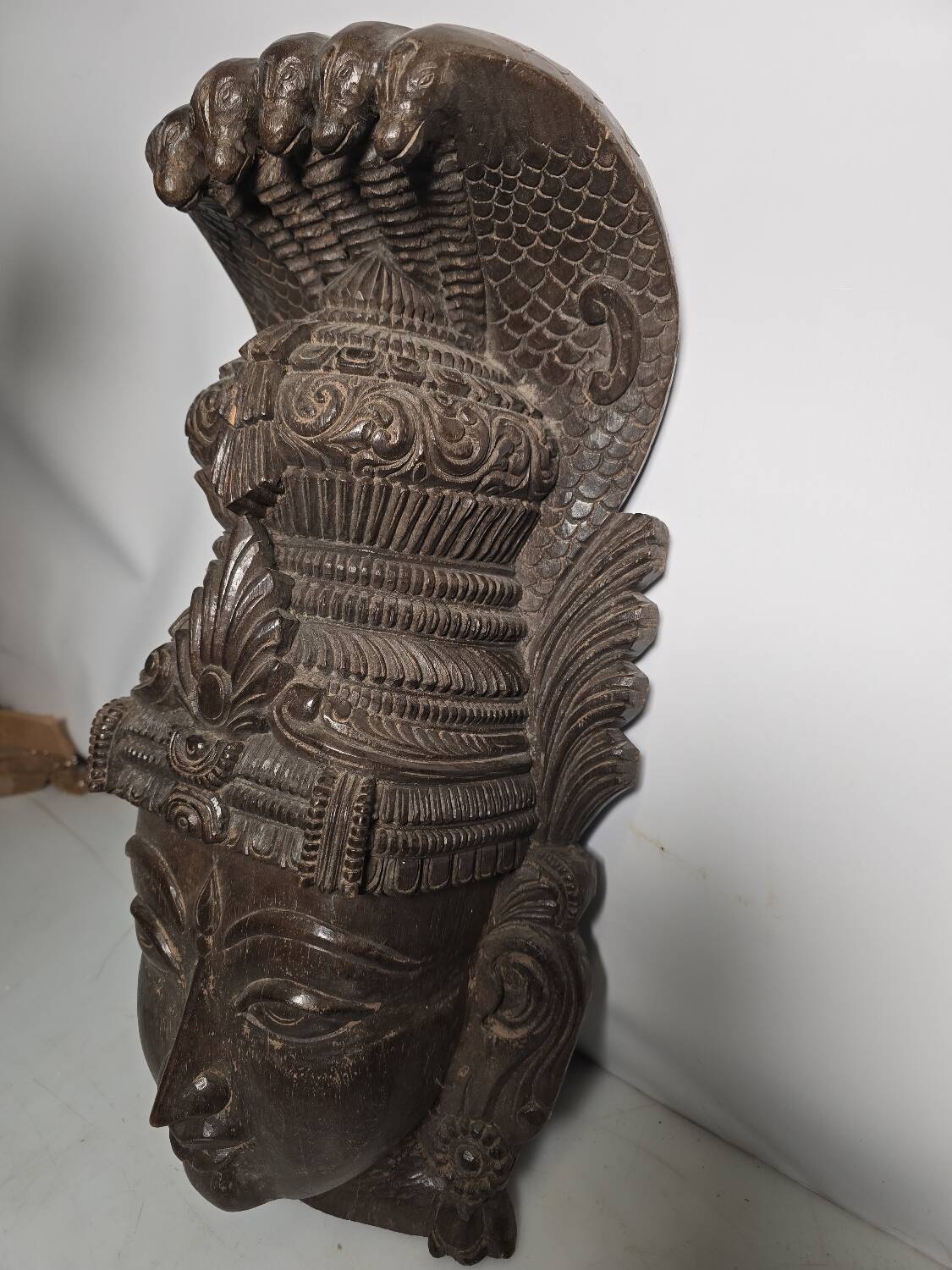 Ancient Indian carved wooden mask sculpture of a deity with a cobra.