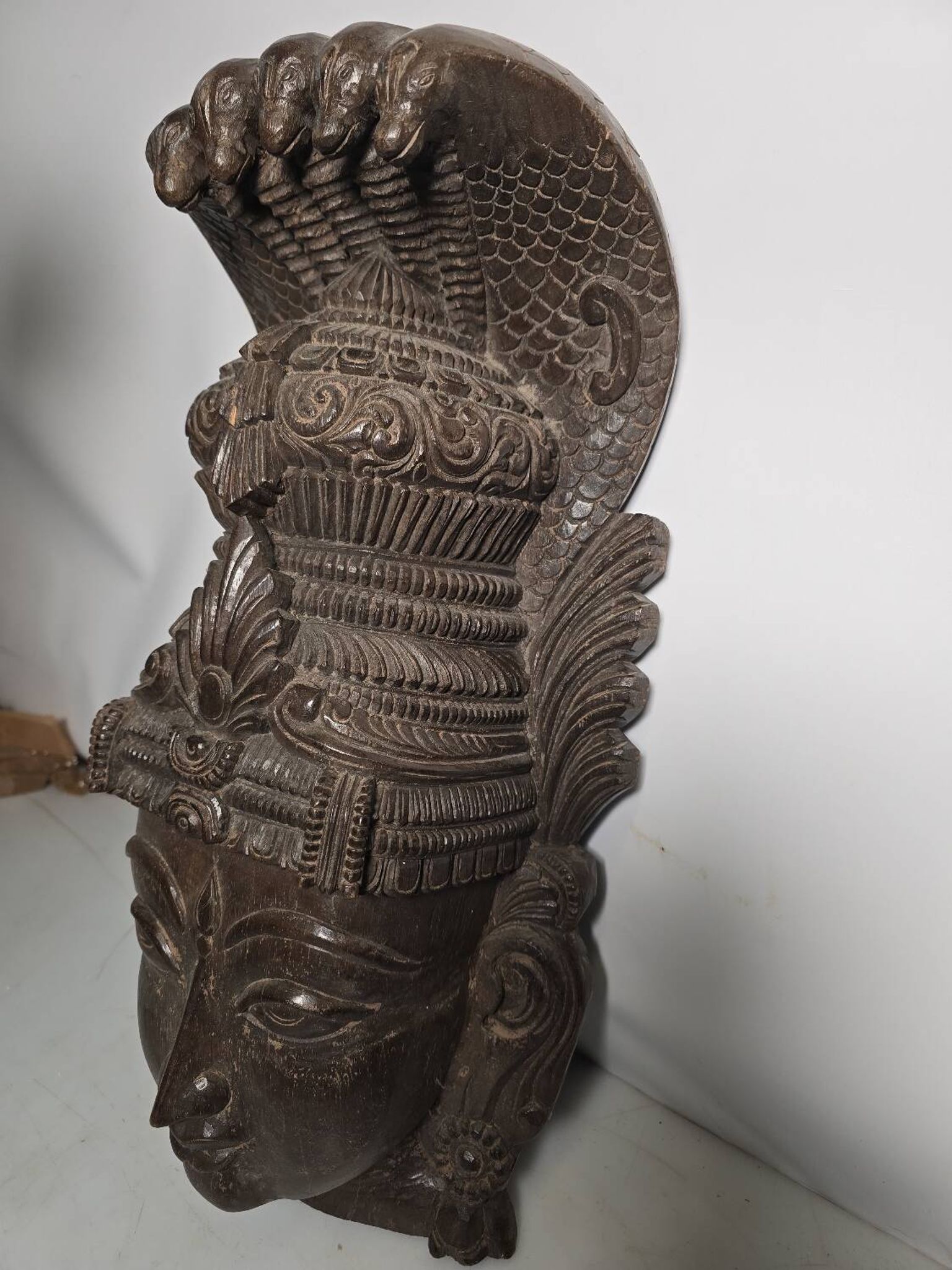 Ancient Indian carved wooden mask sculpture of a deity with a cobra.