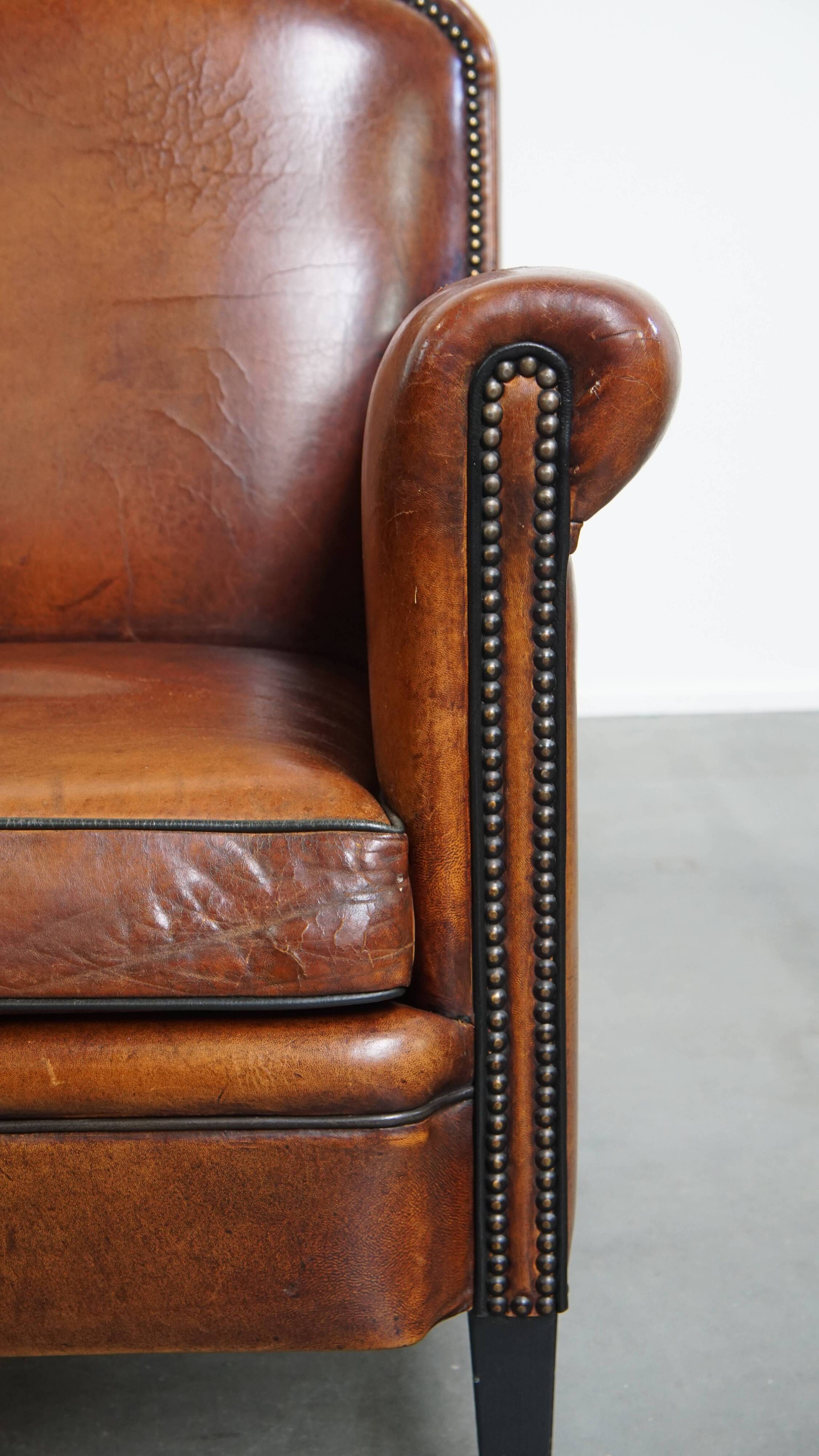 Sheepskin leather armchair in a cognac color with black piping