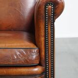 Sheepskin leather armchair in a cognac color with black piping