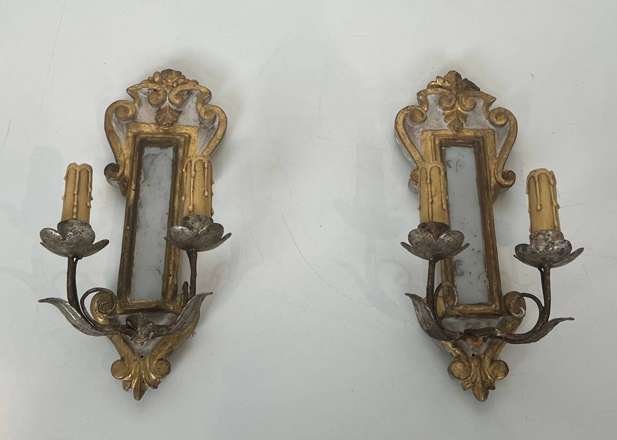 Pair of wall sconces in carved wood and silvered and gilded patinated metal with a central mirror.