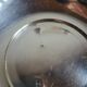 Shallow round metal plate with pearl bead decoration.