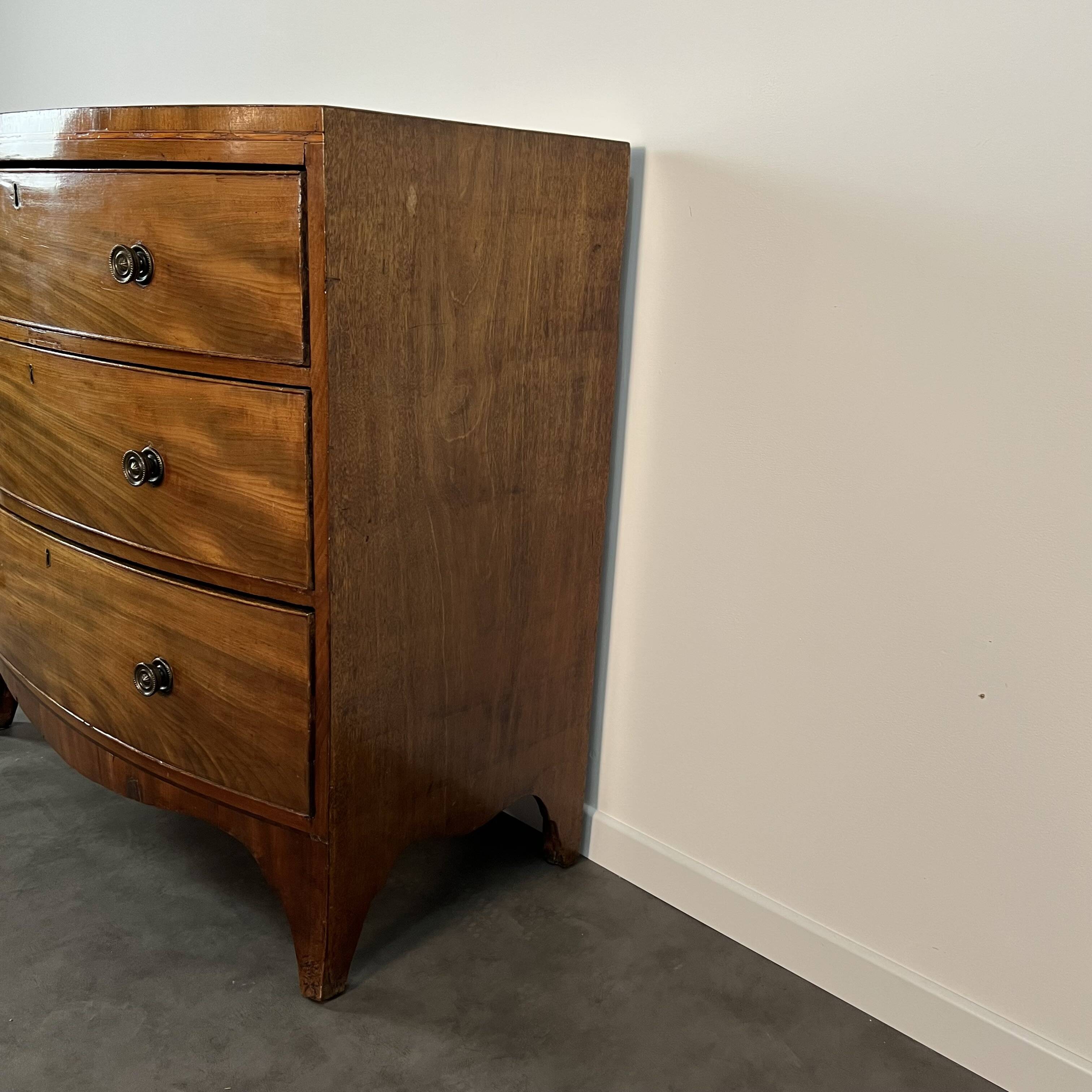 English commode from the George III Regency period, bombe shape in mahogany veneer.