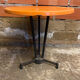 Vintage bistro table with black cast iron base and orange bakelite top, 1950s