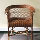 Woven rattan armchair with armrests.