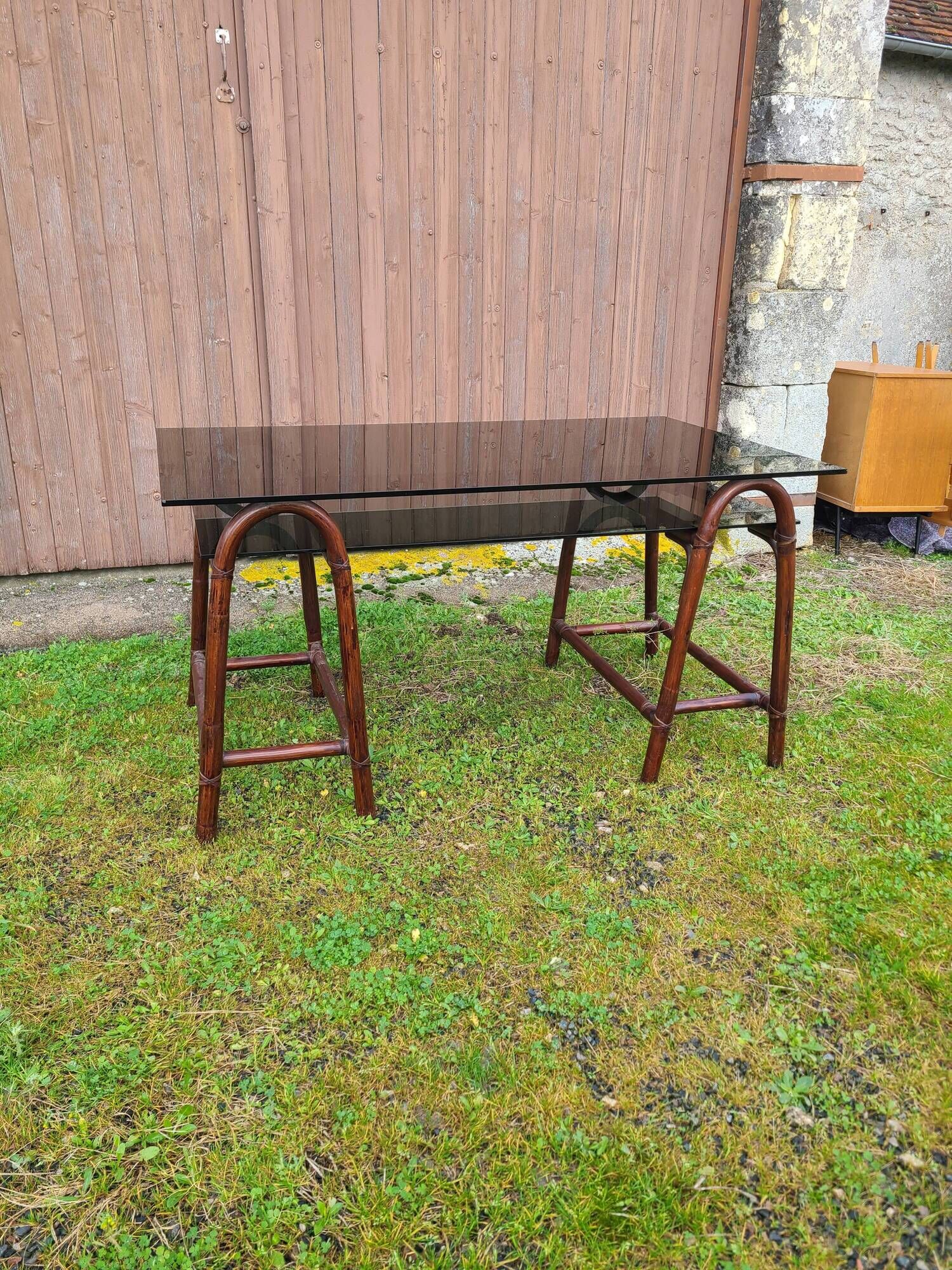 Smoked glass desk on rattan legs and leather detail