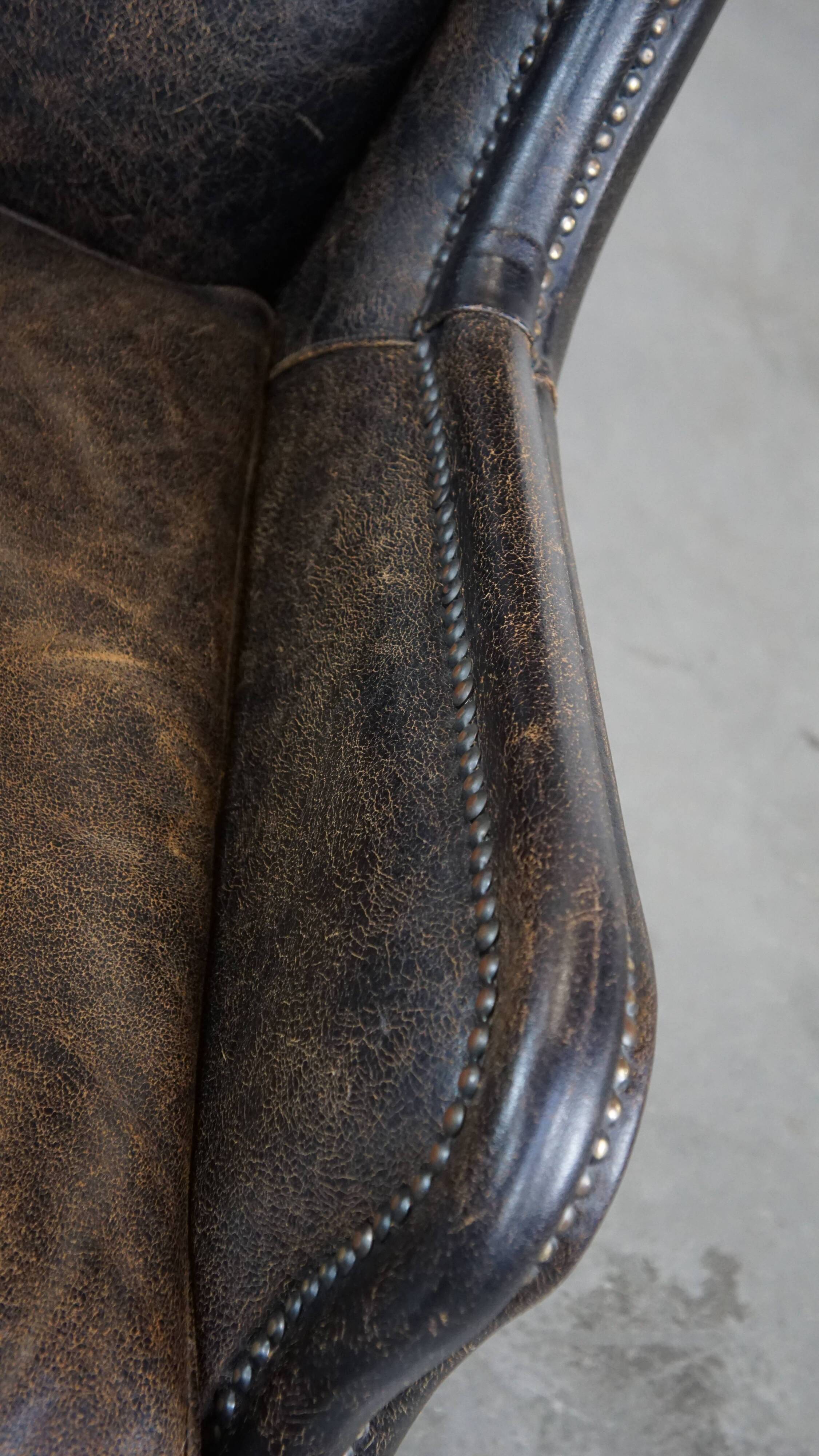 Black cow leather armchair finished with decorative nails, industrial style