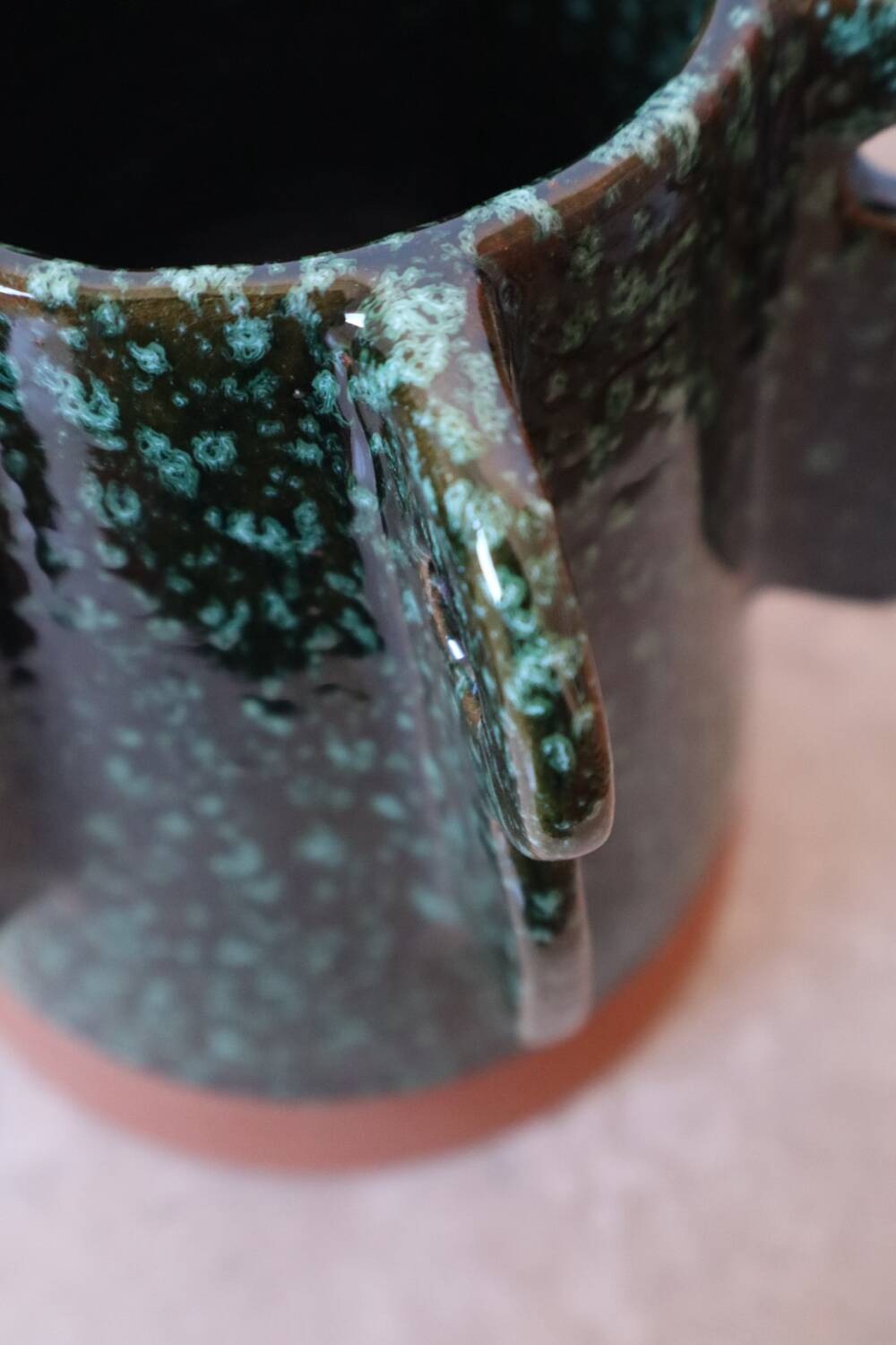 Sculptural ceramic vase with dark green glaze and shimmering highlights